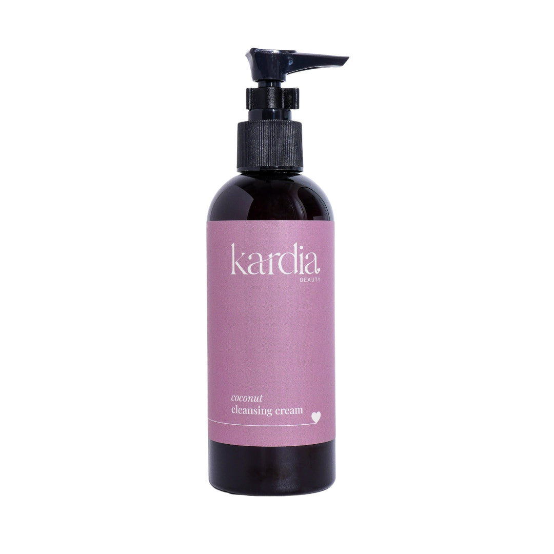 Elegant dark bottle of Kardia Beauty Coconut Cleansing Cream with a pump dispenser, showcased on a white background. The label features a soft purple gradient, emphasizing the product's gentle formula suitable for a luxurious skincare routine.