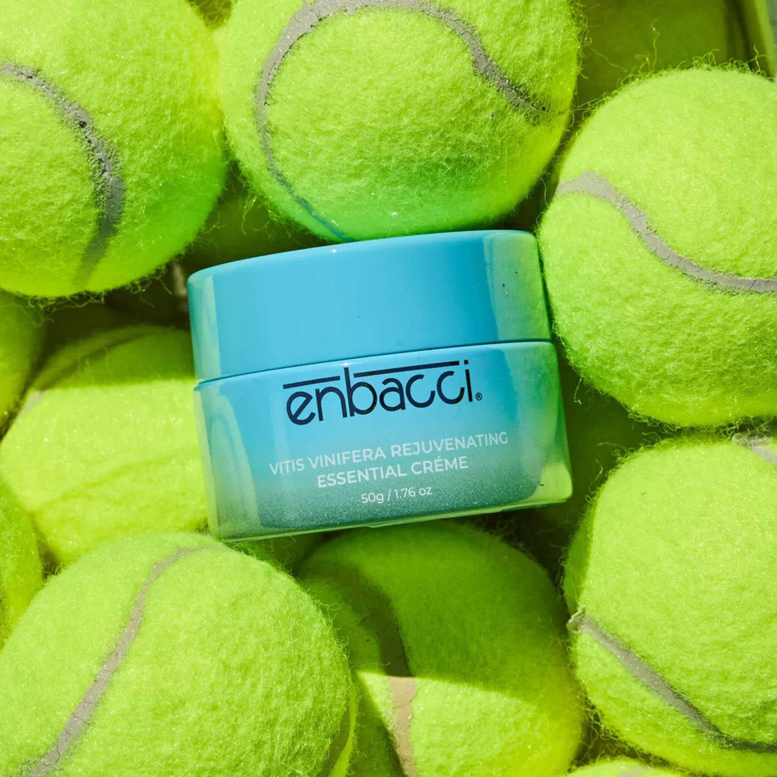 Enbacci Skincare Vitis Vinifera Rejuvenating Essential Crème nestled in tennis balls, lightweight daily moisturiser for antioxidant-rich hydratio