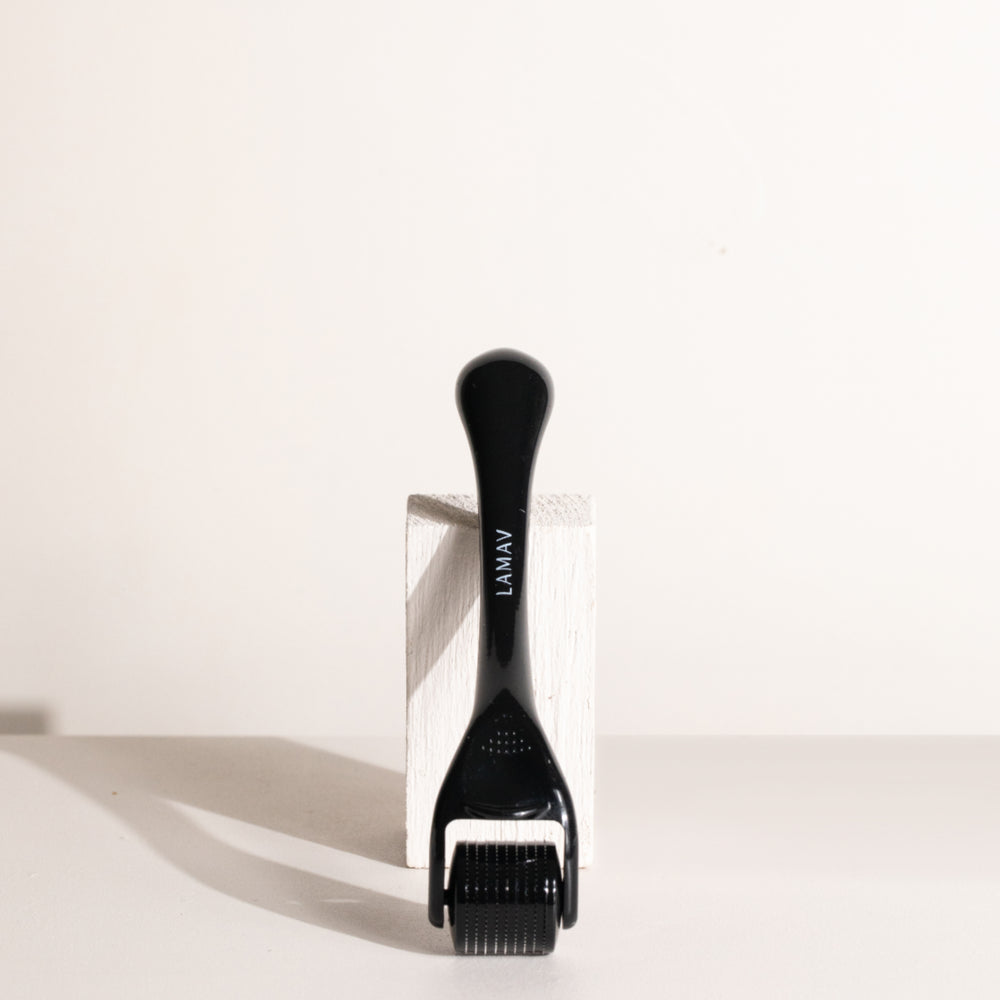 A black derma roller with a curved handle and a black micro-needle roller head, isolated on a white background. The device is commonly used in skincare routines to promote hair growth, collagen production, or enhance the absorption of topical products.
