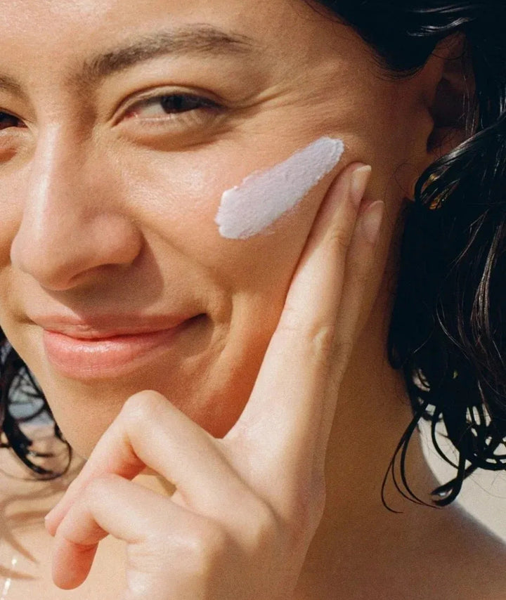 Woman applying Mother SPF Face + Body SPF 50 sunscreen for daily UV protection and healthy-looking skin