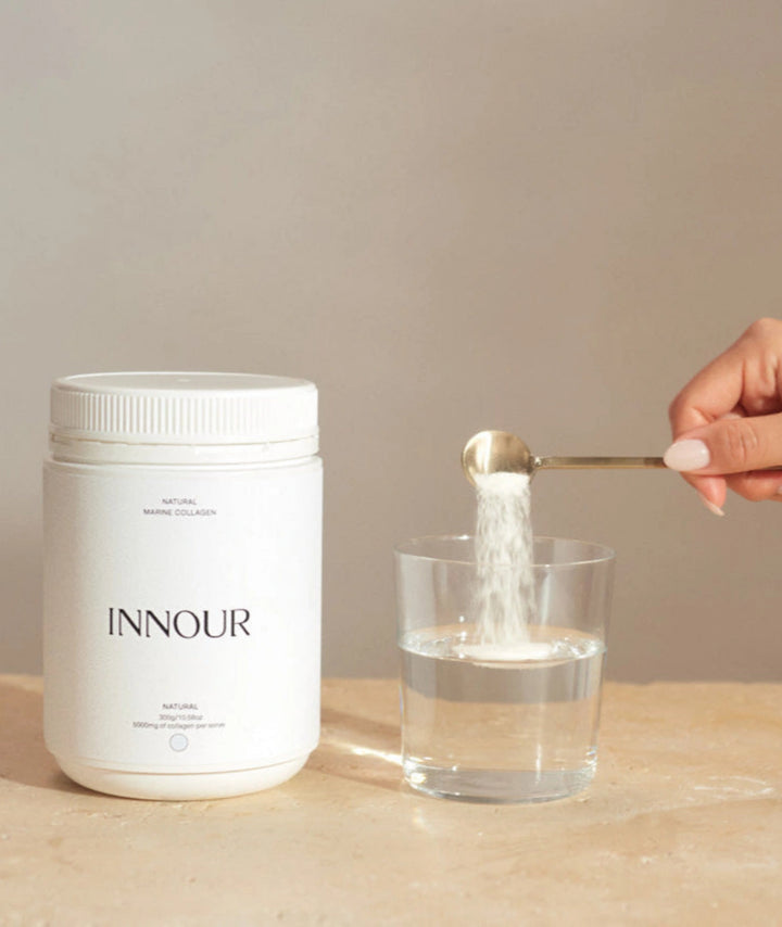 INNOUR collagen supplement for healthy, glowing skin with a glass of water and a spoonful of marine powder collagen being poured into a glass.