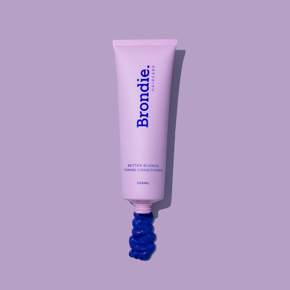Squeeze of deep purple Better Blonde toning shampoo against a blue background, highlighting the rich color and texture.