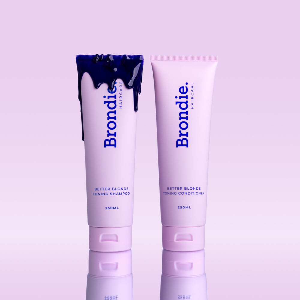 Brondie Haircare's Better Blonde toning shampoo and conditioner duo with spilled violet product, emphasizing the toning effect.