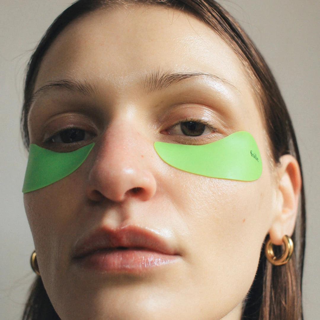 Person wearing green reusable eye masks australia with a neutral background