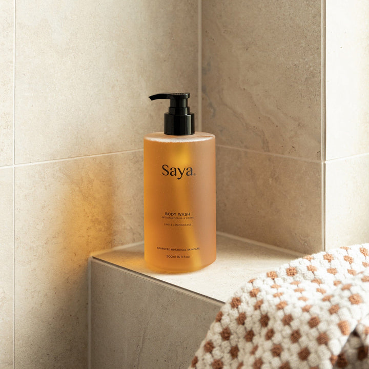 Saya Skincare All Natural Body Wash Next to a fluffy towel and beige tiles.