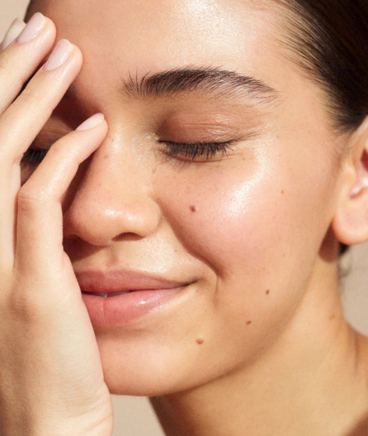 Close-up of a person's face with a hand on their cheek, showing skin texture.