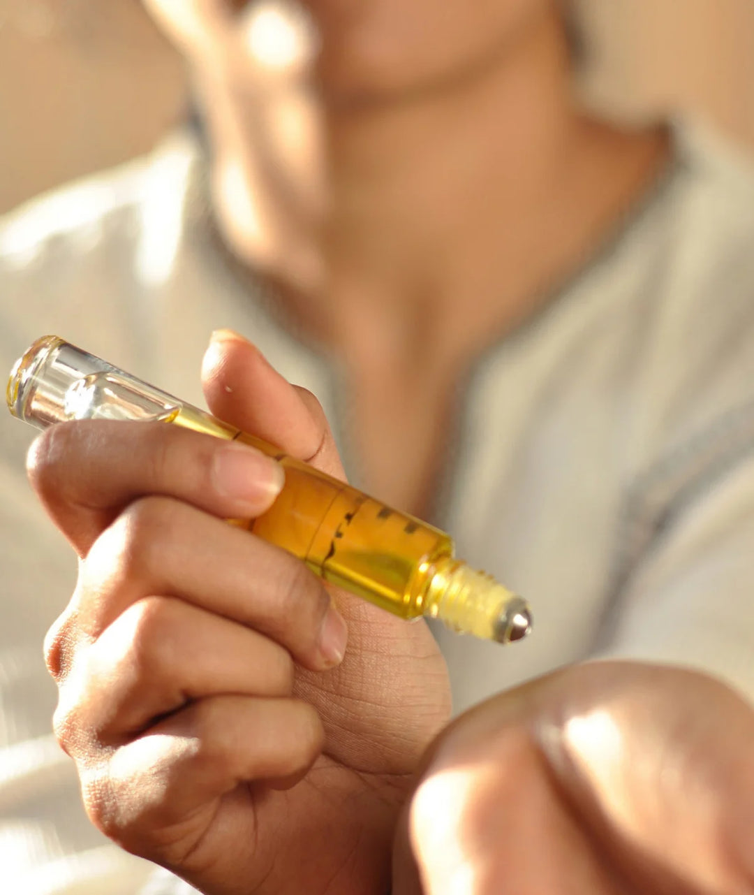 Applying Serene Bodyhealth Amplify essential oil perfume rollerball to skin.