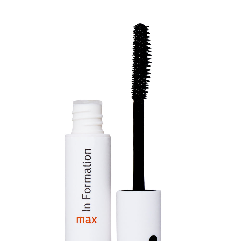 The image shows an open white cylindrical bottle labeled "In Formation" with the word "max" in orange below it. Next to the bottle is an applicator with a black wand and a spiral-bristled brush that is coated with a product, this is a hair tool. This product is for hair care, designed to tame flyaways and tame frizzy hair—this is supported by the wand's resemblance to a mascara applicator.