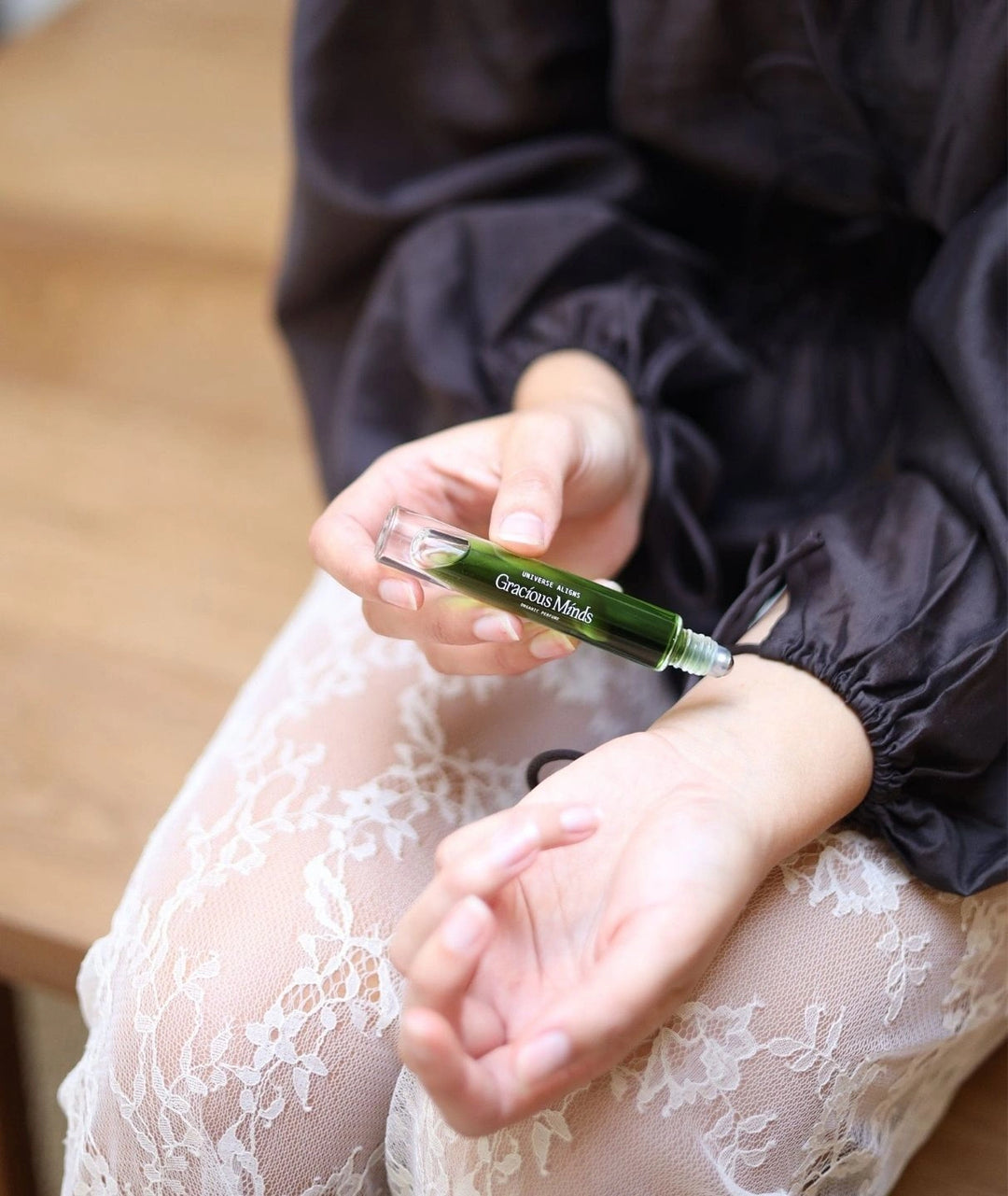 Close up of a woman applying Gracious Minds Universe Aligns organic perfume to her wrist.