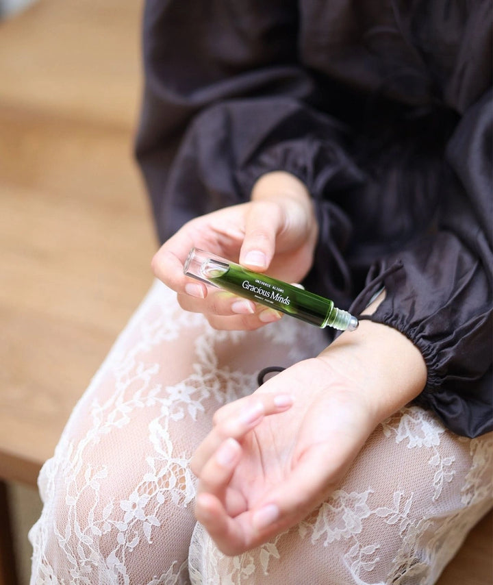 Close up of a woman applying Gracious Minds Universe Aligns organic perfume to her wrist.