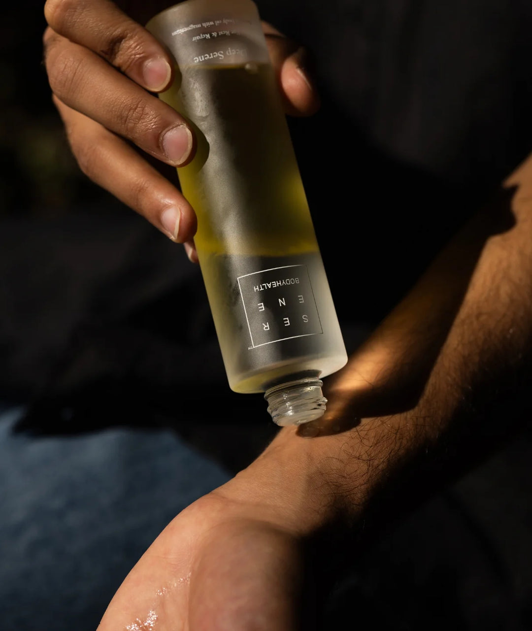 Person applying Serene Bodyhealth Deep Serene magnesium body oil onto forearm for relaxation.