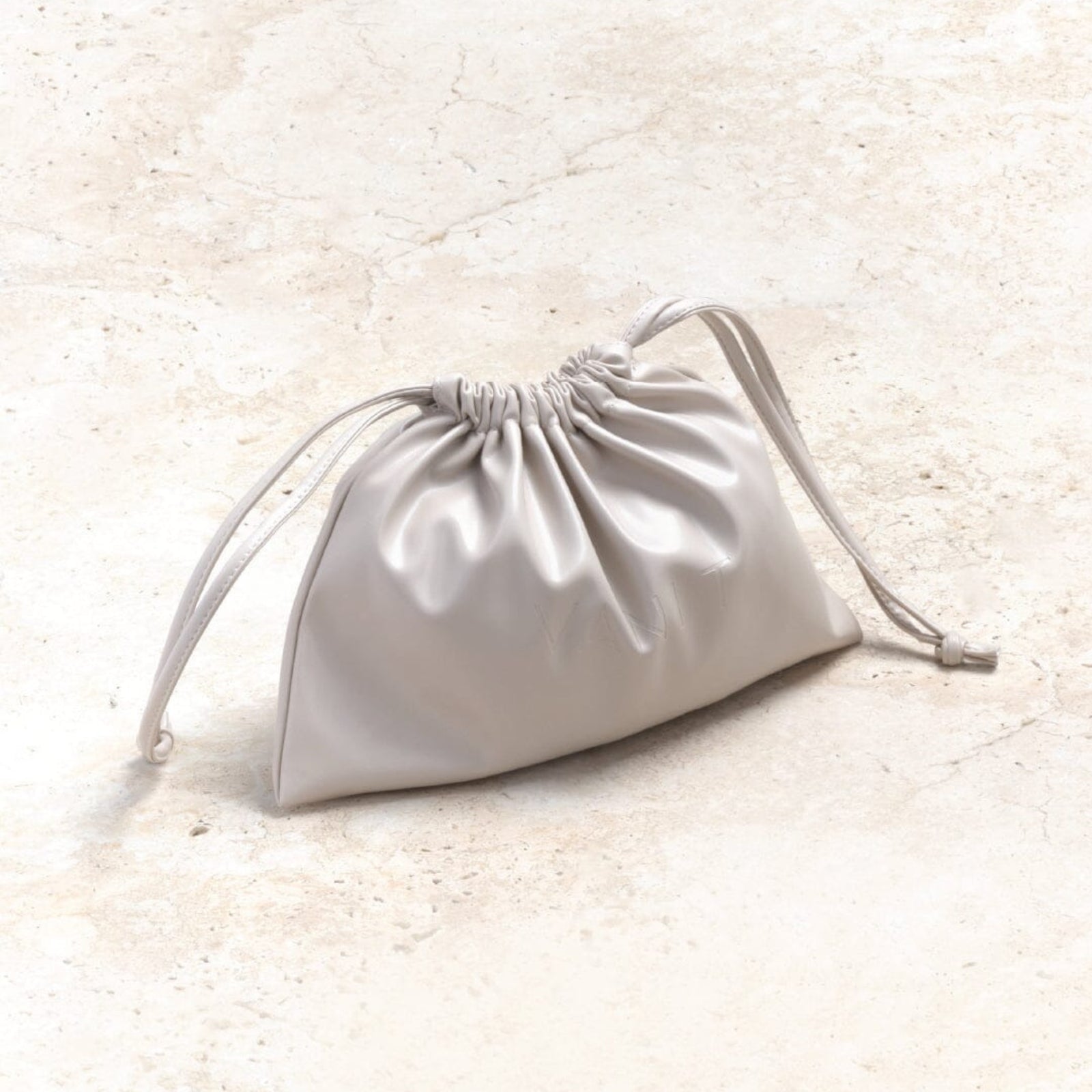 Minimalist drawstring beauty bag in pearl-white, styled against a textured neutral background. Perfect for storing skincare, makeup, or travel essentials, this modern accessory blends elegance with practicality for everyday use.