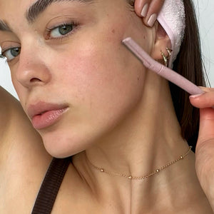Close-up of a young woman using a pink BondiBlades dermaplaning razor for facial exfoliation, available at VAMS Beauty, an Australian online beauty shop known for premium skincare tools and products.