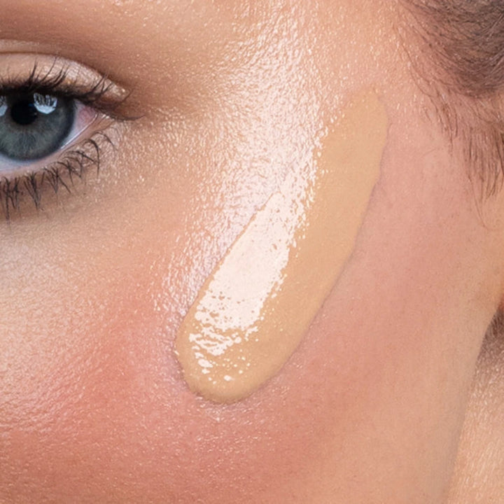 Close-up of a woman's face with bronzing drops applied to cheek