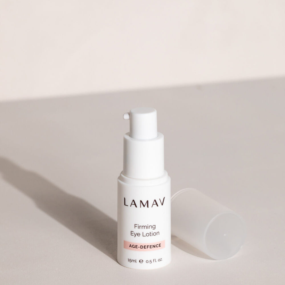 Bottle of LAMAV Organic Firming Eye Lotion, part of the AGE-DEFENCE line, 15ml. The product is presented in a sleek, white dispenser with clear labeling, designed for reducing the appearance of fine lines around the eyes.