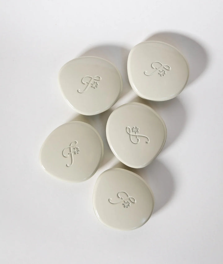 Forest Fig Solid Perfume by Fleurac — Five closed pebble compacts with logo | Refillable eco luxury solid fragrance