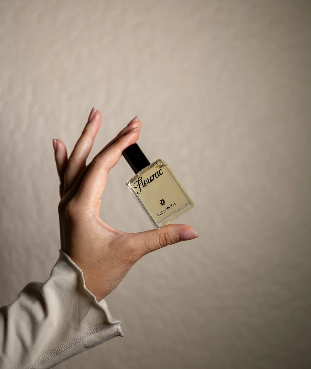 Woodpetal Perfume by Fleurac — Hand holding clear glass spray bottle | Warm woody floral eau de parfum