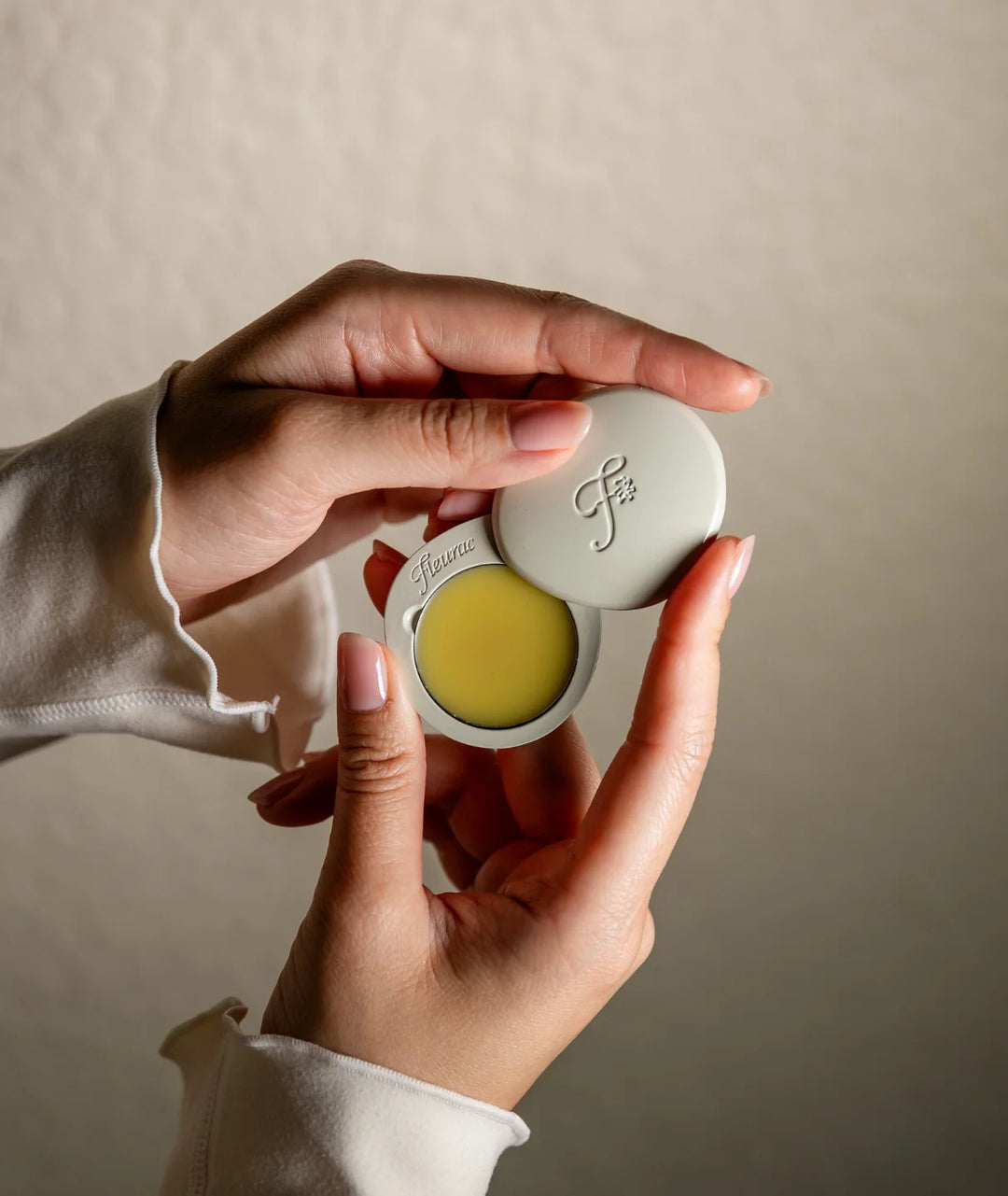 Fleurac Woodpetal Solid Perfume — Hands holding open pebble compact with solid fragrance balm