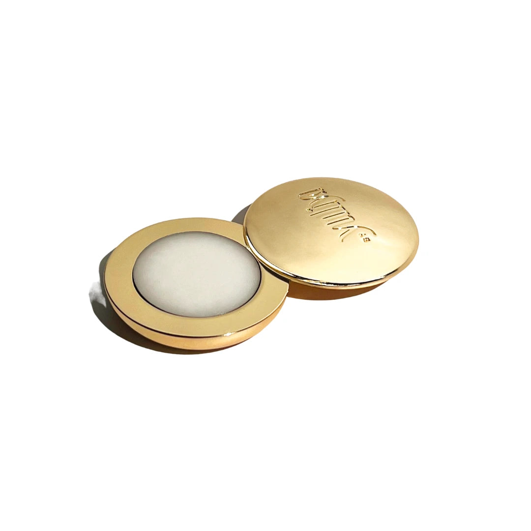 Gold compact solid fragrance for women with perfume balm inside on a white background.