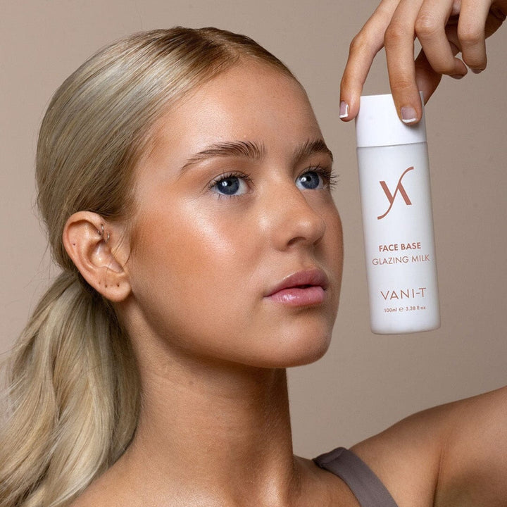 Woman holding a bottle of Vani-T Face Base Glazing Milk Australia with a neutral background