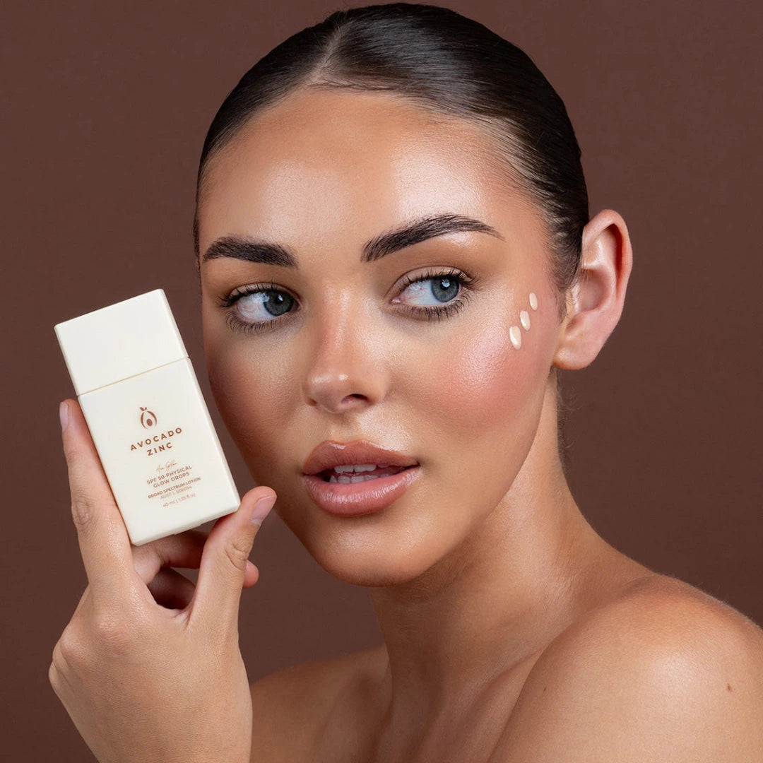 Woman holding best glow drops for face product with a brown background
