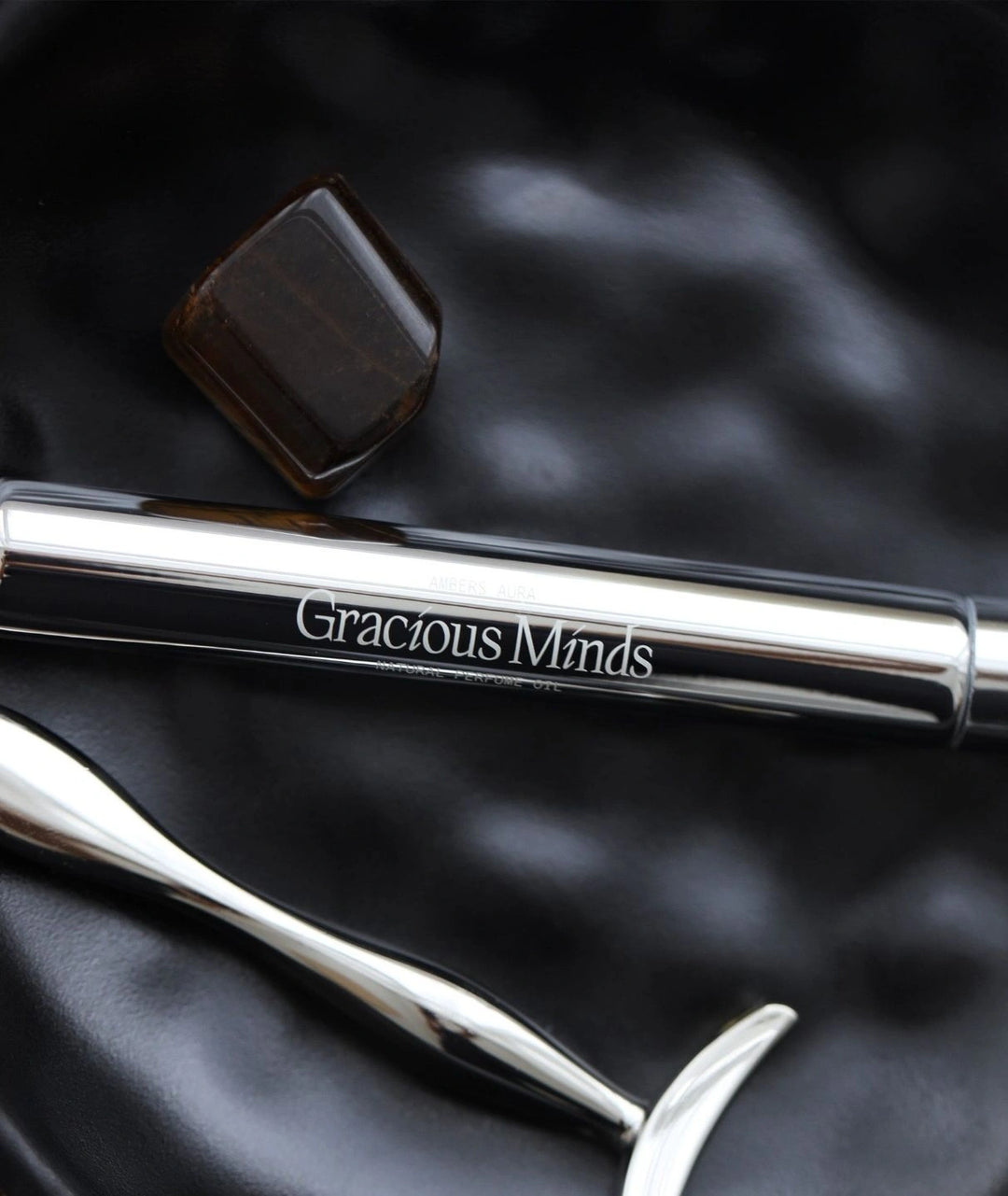 Gracious Minds Ambers Aura natural perfume oil roller with a brown crystal.