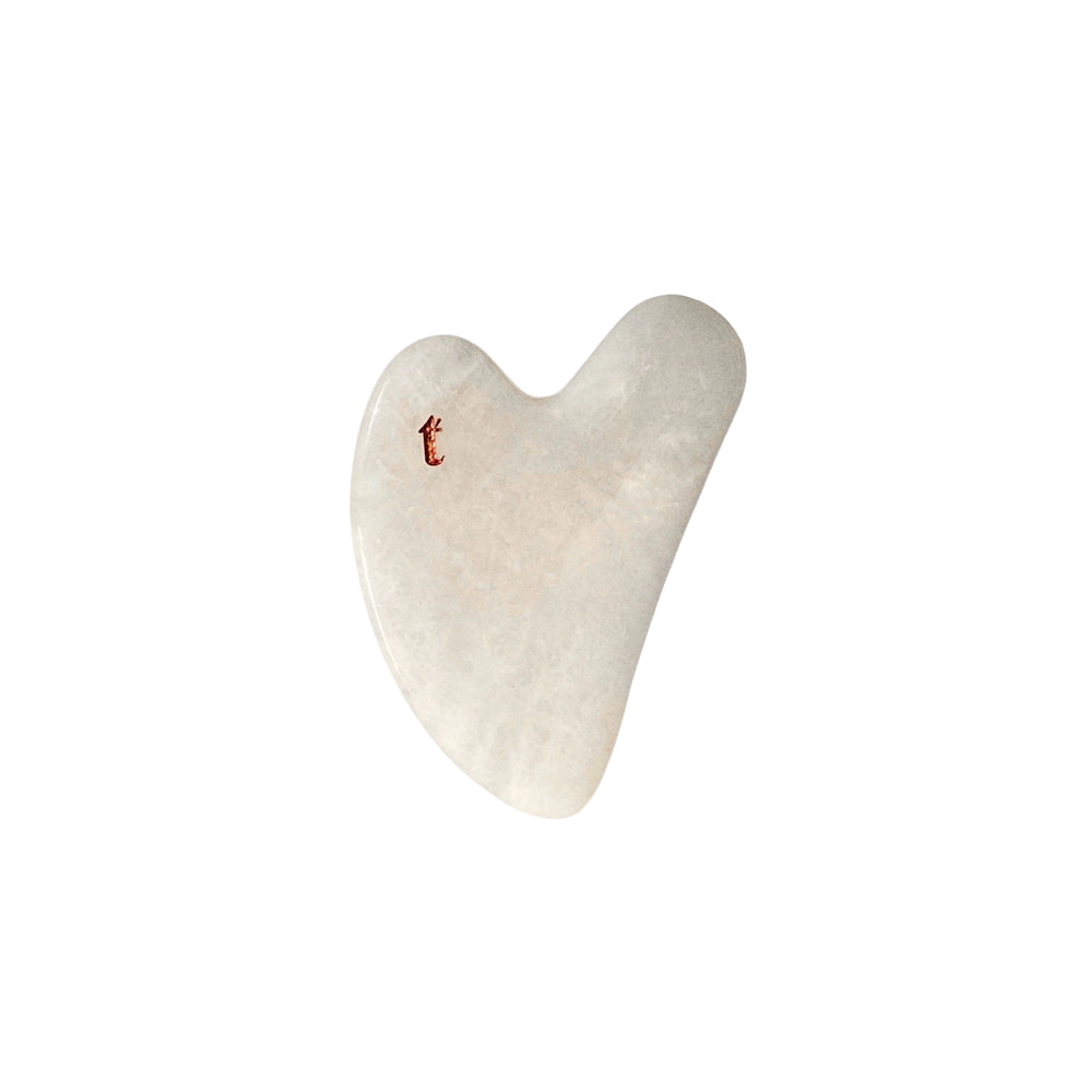 White gua sha stone with natural veining, engraved with a golden 'T', it’s an anti-aging skincare tool available at an Australian online beauty shop Vams Beauty.
