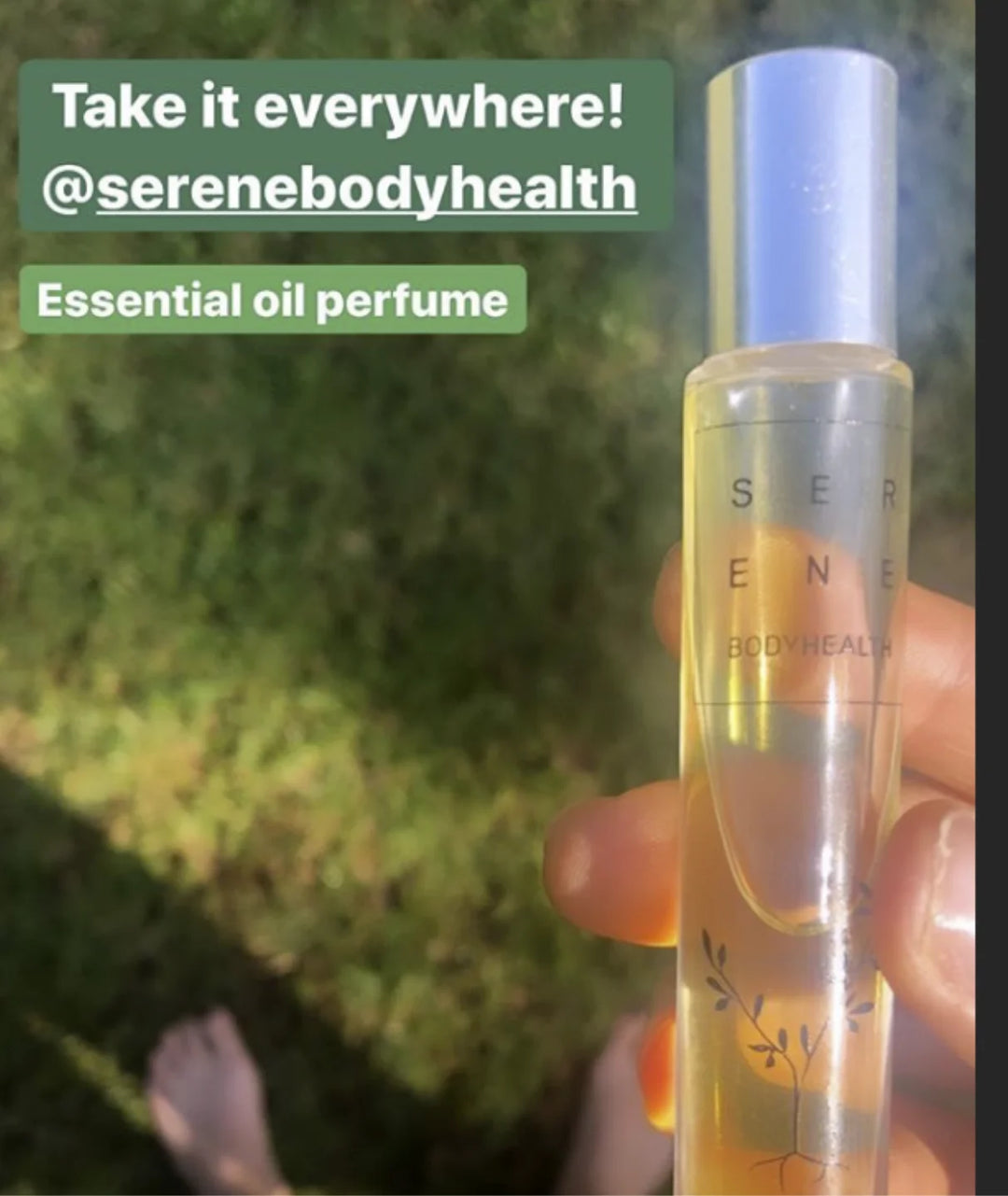Hand holding Serene Bodyhealth Ground essential oil perfume rollerball bottle outdoors.