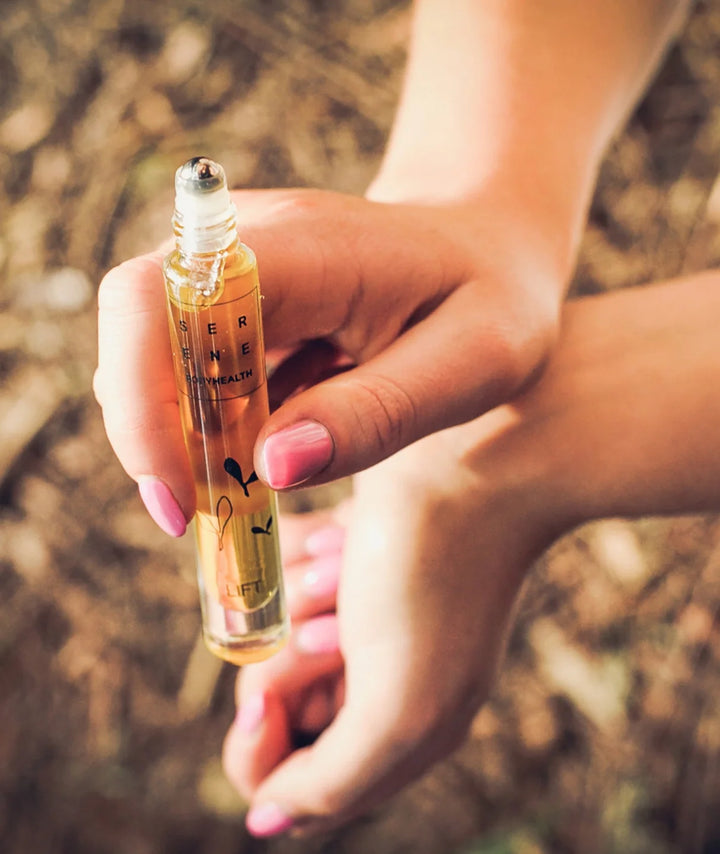 Hand holding Serene Bodyhealth Lift essential oil perfume rollerball outdoors