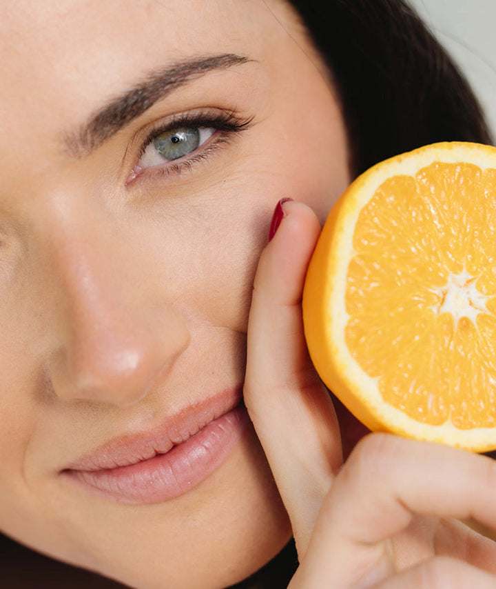 Close-up beauty portrait with fresh orange representing the natural summer fruits flavour of Innour Marine Collagen sachets for skin wellness and hydration support.