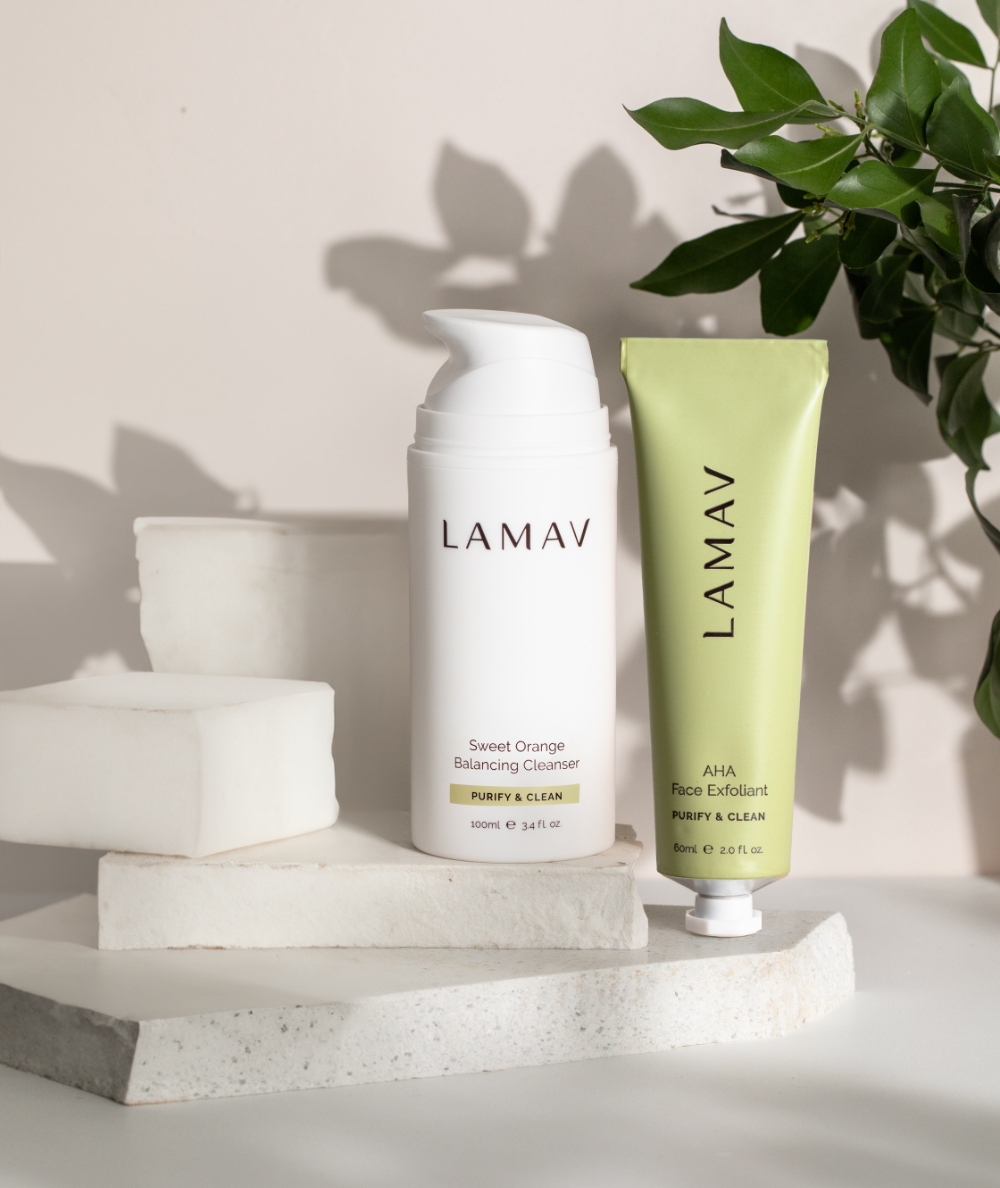 LAMAV Cleanse and Polish Pack resting on stone blocks with botanical leaf shadows. Organic exfoliating skincare duo.