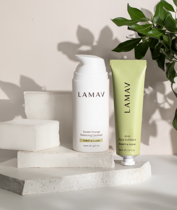 LAMAV Cleanse and Polish Pack resting on stone blocks with botanical leaf shadows. Organic exfoliating skincare duo.