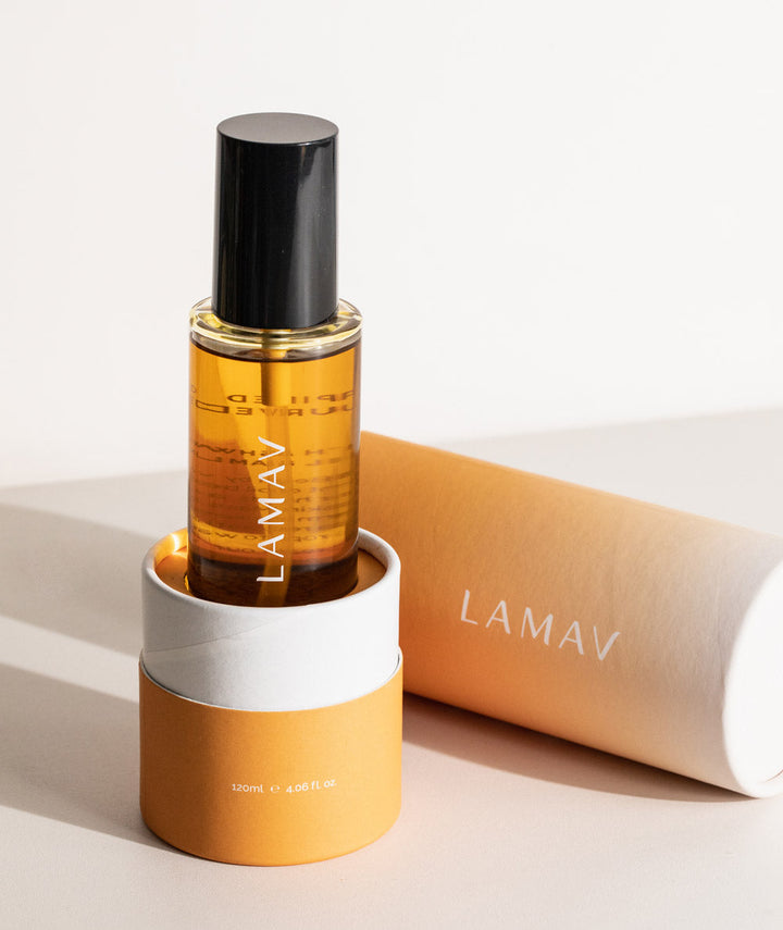 LAMAV Ayurvedic Body Oil Nourish. Orange bottle displayed in matching cylindrical base.