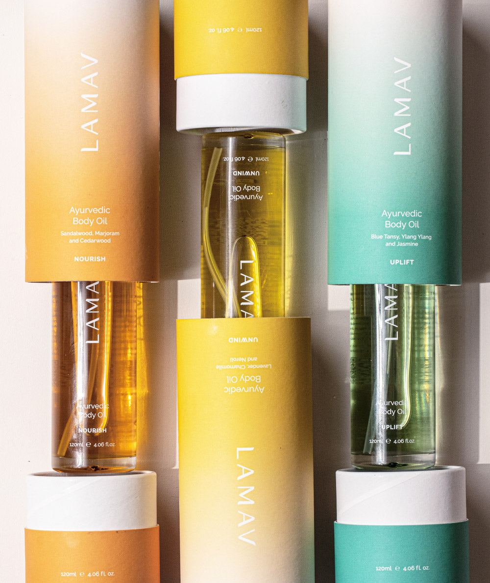 Top-down view of LAMAV Ayurvedic Body Oils Trio inside orange, yellow, and green tube boxes.
