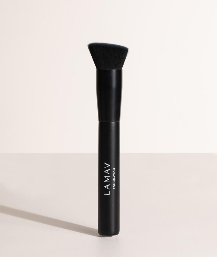 Upright LAMAV Vegan Foundation Brush on a minimalist surface. Features an angled head for liquid cosmetics.