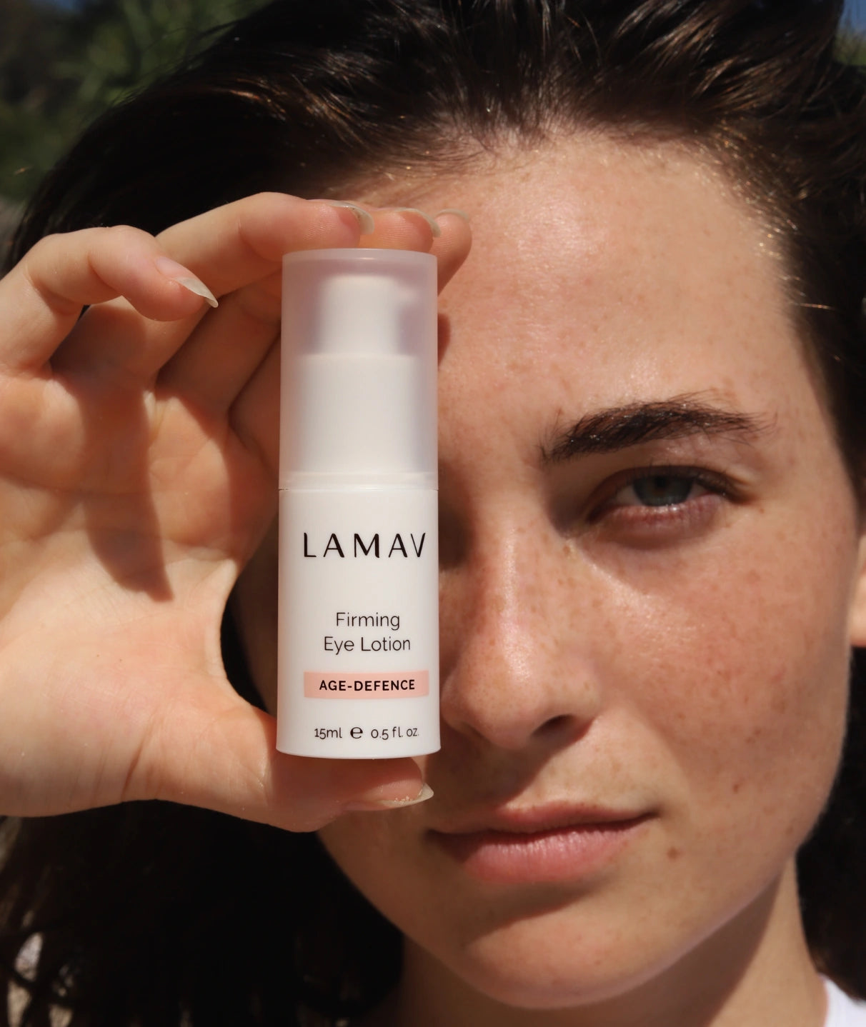 Woman holding LAMAV Firming Eye Lotion, a natural eye treatment formulated with Wakame, Paracress and Caviar Lime to help firm, smooth and reduce the appearance of fine lines around the eyes.