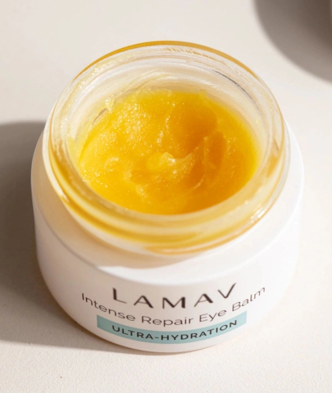 Close-up of LAMAV Intense Repair Eye Balm showing rich yellow texture. Nourishing eye treatment for fine lines.
