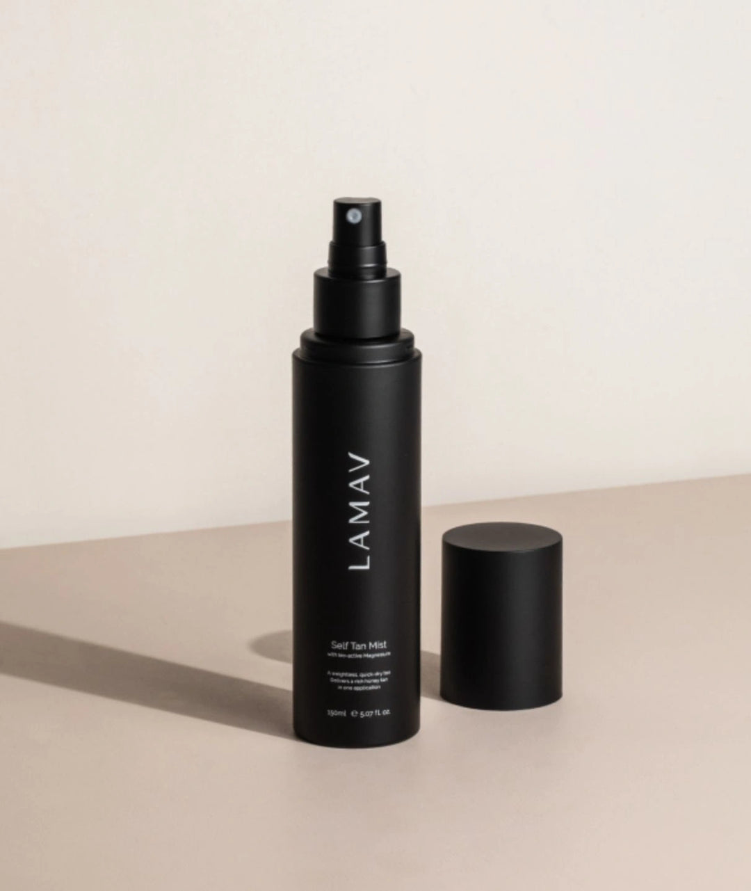 LAMAV Self Tan Mist bottle with cap removed on a beige surface showing product details.