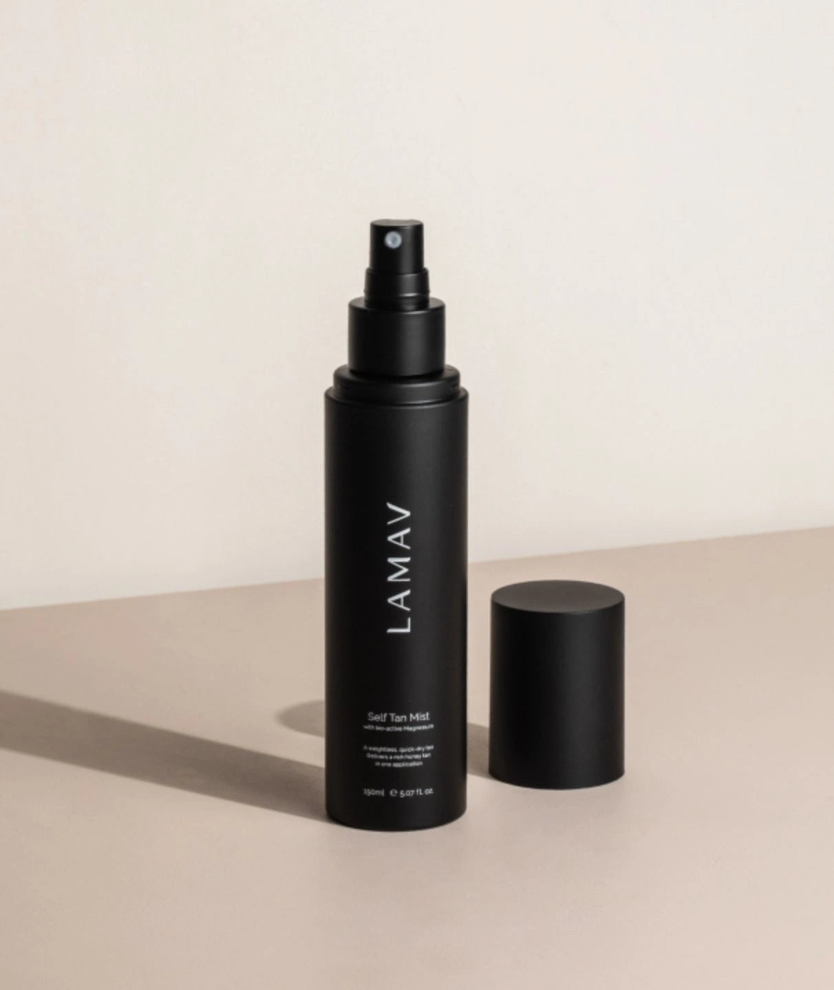 LAMAV Self Tan Mist bottle with cap removed on a beige surface showing product details.