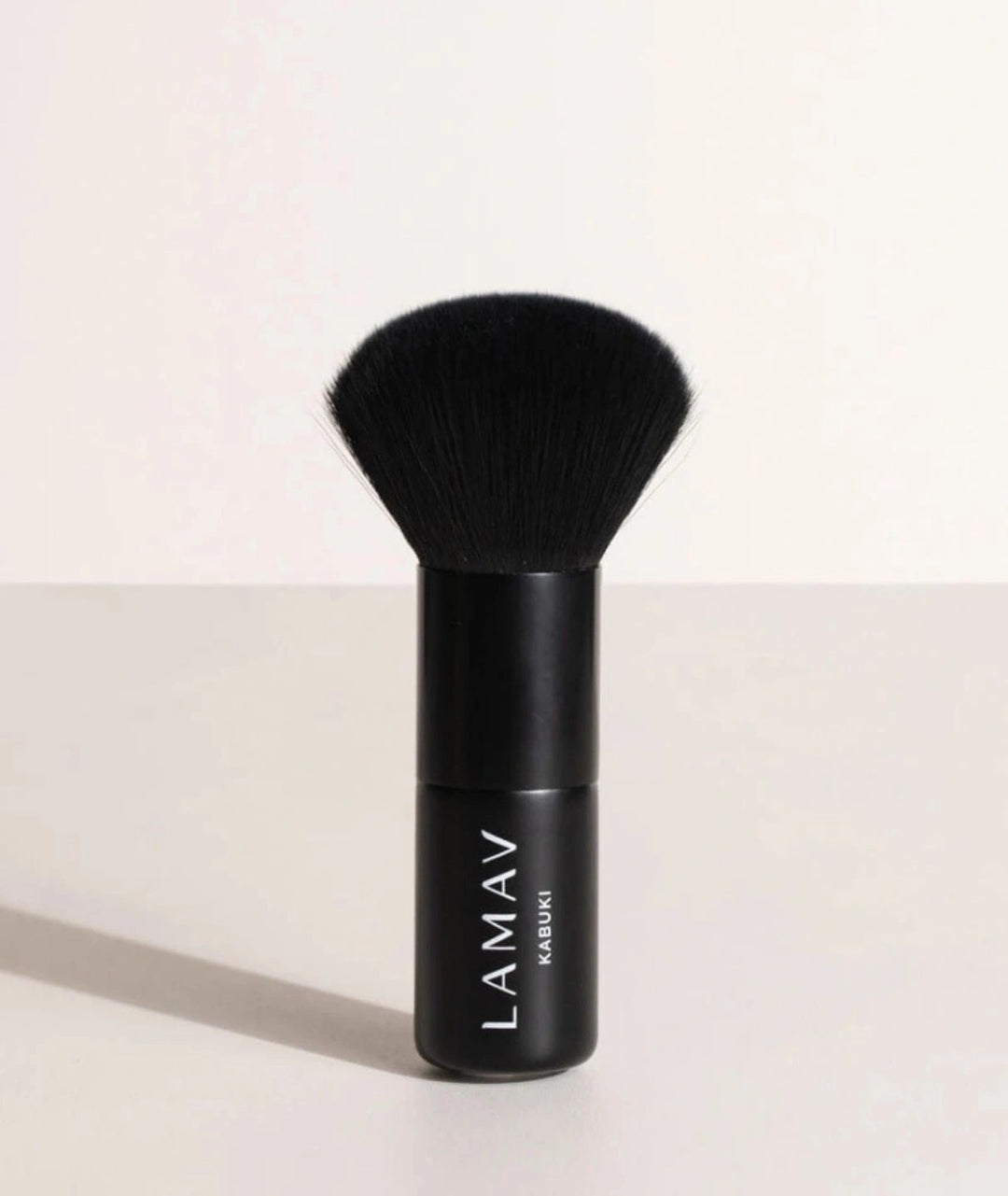 LAMAV Vegan Kabuki Brush standing upright. Black makeup brush with soft bristles for flawless powder blending.