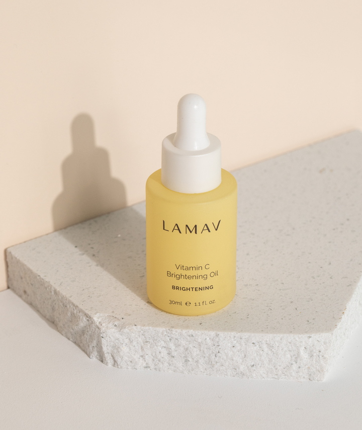 LAMAV Vitamin C Brightening Oil 30ml on a stone slab. Brightening face serum in a yellow bottle.