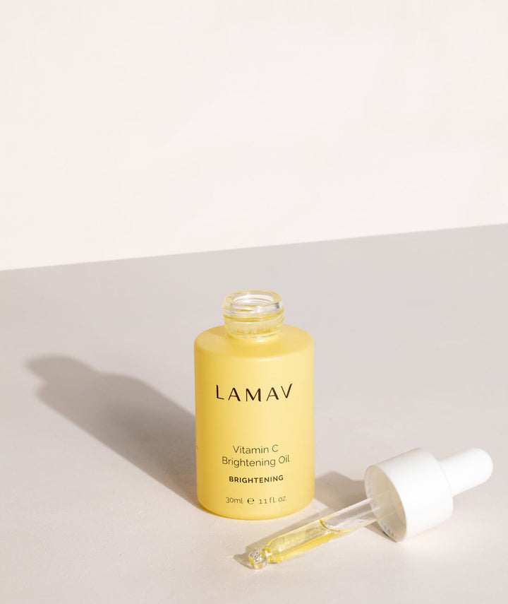 Open LAMAV Vitamin C Brightening Oil 30ml bottle and dropper applicator on a minimalist beige surface.