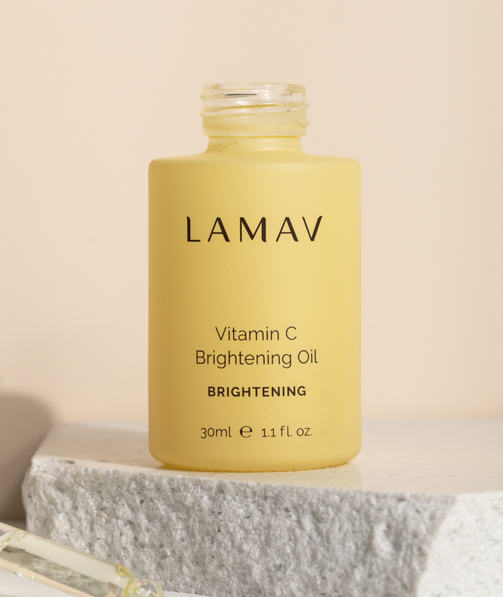 Open LAMAV Vitamin C Brightening Oil 30ml bottle resting on a white textured stone display block.