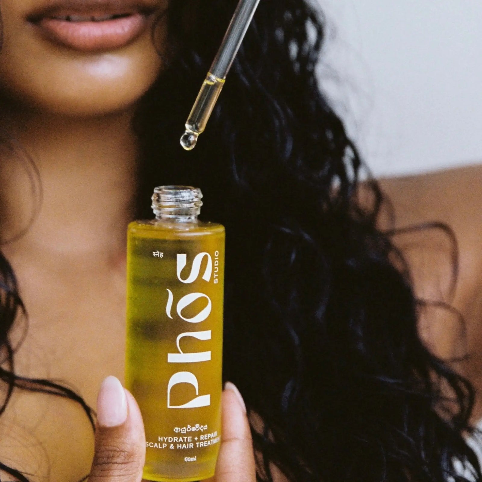 Model using a dropper to apply Phos Hydrate & Repair Scalp & Hair Treatment, available at VAMS Beauty. This 60ml hair oil nourishes and repairs hair, promoting hydration and overall hair growth with a natural formula.