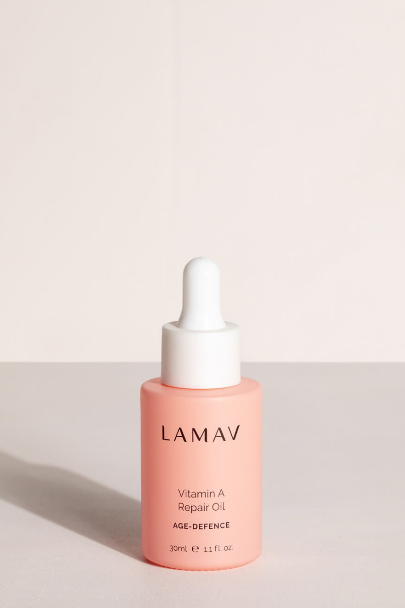 Pink bottle of Certified Organic LAMAV Vitamin A Repair Oil for ageing, mature skin on a light beige background