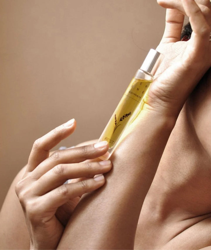 Woman holding Serene Bodyhealth Rest essential oil perfume rollerball along her inner arm.