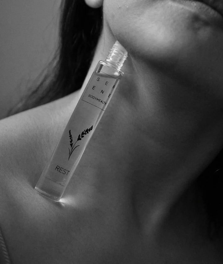 Serene Bodyhealth Rest essential oil perfume rollerball resting against woman's neck and collarbone.