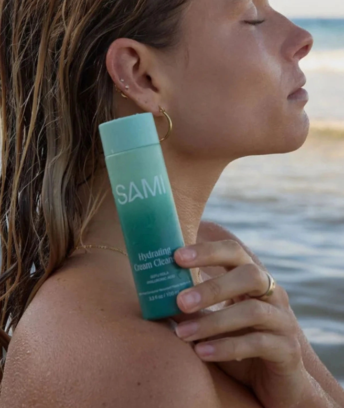 Hydrating Cream Cleanser by SAMI — model holding bottle by ocean | soothing cleanser for dewy skin