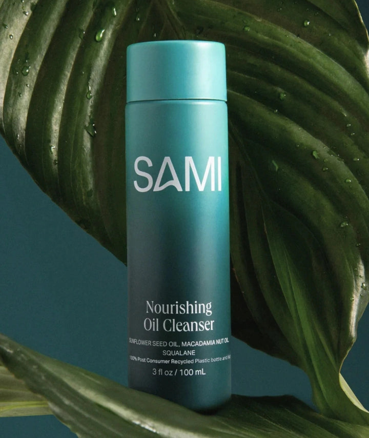 SAMI Nourishing Oil Cleanser 100ml bottle on green leaves highlighting clean botanical formula.