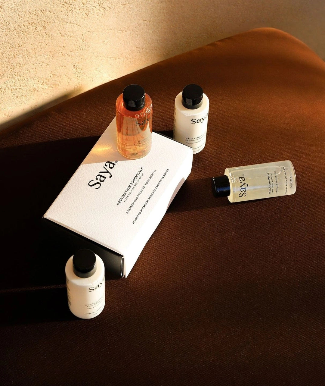 Saya Destination Essentials travel kit with Argan Conditioner & botanical body care on a brown surface. Made in Noosa.
